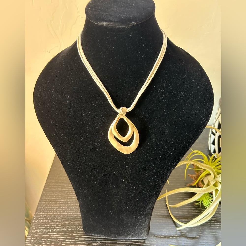 Gold Tone Pendant On Cream Colored Rope